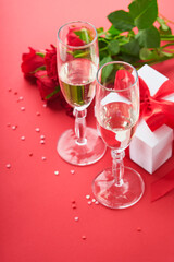Valentines Day or Romantic dinner concept. Romantic table setting, silverware, wine glasses, gift box, roses and symbol of love red heart on red background. Romantic Dinner Valentines Day concept.