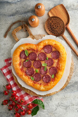 Valentines day heart shaped pizza with mozzarella, pepperoni and basil, wine bottle, two wineglass, gift box on light grey background. Idea for romantic dinner Valentines day. Top view. Mock up.