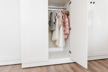 Hangers with stylish clothes for a girl in the white closet.