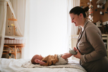 Overweight mother changes baby's cloth diaper, eco-friendly natural swaddling system, replacement...
