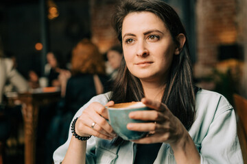 Portrait of a beautiful brunette woman drinking coffee in a coffee shop.