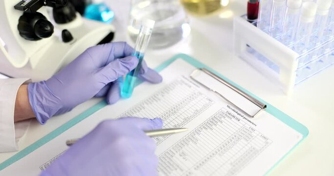 Scientist doctor with test tube with blue liquid and chemical composition data table closeup
