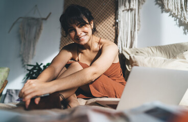 Content mature Hispanic woman using laptop in bed