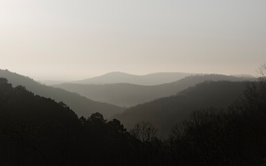 Black and White image of hills with varying gradients in saturation from shadows, light, and fog.