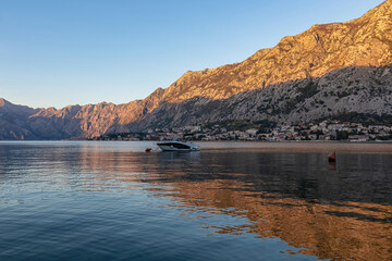 Naklejka premium Panoramic view of the bay of Kotor during sunrise in summer, Adriatic Mediterranean Sea, Montenegro, Balkan Peninsula, Europe. Fjord winding along the coastal towns. First sunbeams on Lovcen mountains