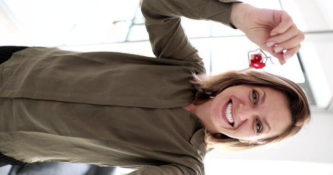 Joyful woman records video with the keys to new apartment or house vertical