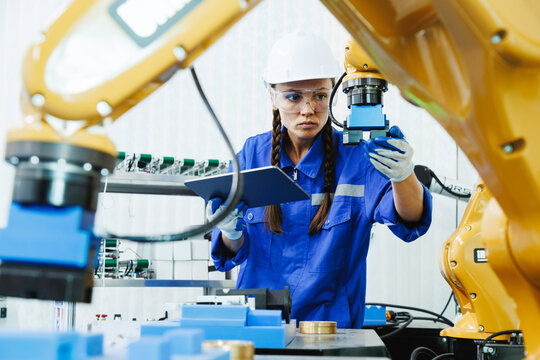 female automation machine engineer student study and inspection control robot arm machine in university or factory workshop. AI robot technology are new innovation trend for manufacturing in industry 