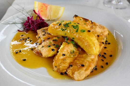 Filete de Espada with banana and passion fruit sauce. The black swordfish - the most typical fish on the island of Madeira. Typical Madeiran dish Espada on white plate served with passion fruit sauce.