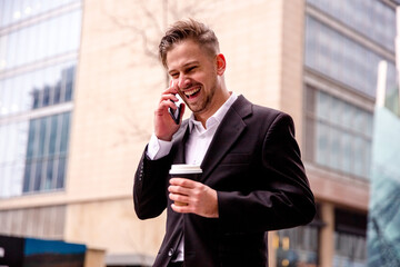 guy in a suit speaks on the phone laughs and walks with coffee in his hands close-up