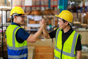 Asian warehouse worker celebrating as they complete their task. They are wearing reflective vest and hard hat.