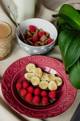 breakfast, cereal with milk, coffee with milk in a faceted glass, beterbrots with chocolate butter, berries and bananas