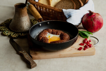 Turkish breakfast, scrambled eggs in a simit bun in a frying pan, coffee in a Turk, fresh bread