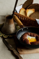 Turkish breakfast, scrambled eggs in a simit bun in a frying pan, coffee in a Turk, fresh bread