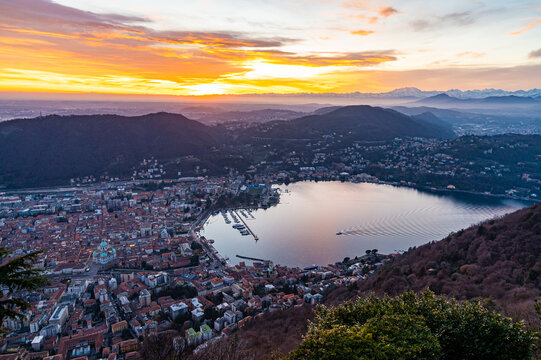 The city of Como, the lakefront and the lake, photographed from Brunate, at dusk, and all the mountains in the background.
