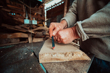 Closeup photo of a senior man outlining wood and preparing it for processing