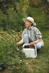 Women pours flowers in the garden with watering can