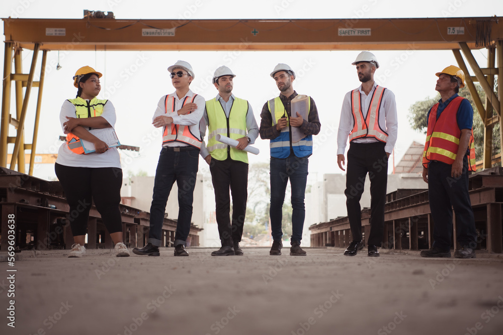 Poster group of architects, construction foremen, and construction engineers review the work and talk about