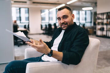 Smiling male manager checking documents spreading hands