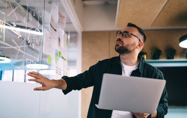 Young man standing with laptop in conference room