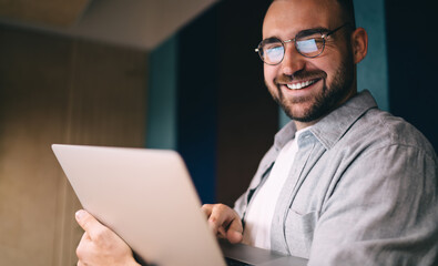 Smiling man in eyeglasses using computer while working