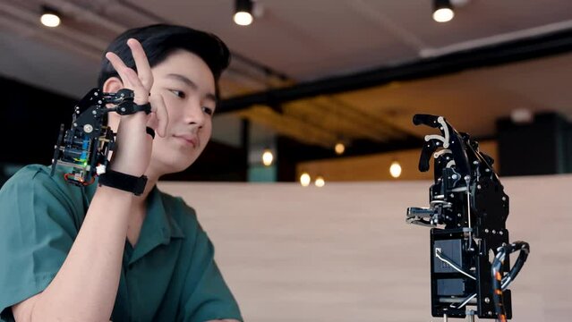 4K, Male student in technology class Wearing hand robotic controller is hand-worn device, moved hand around try control system, had a fun expression on hands control robotic hand in front him.