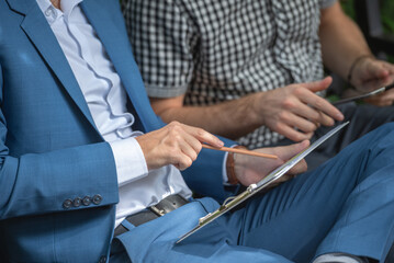 Two businessman or gay sitting at chair in park while using digital tablet and paper work plan for talk discussion team working online togetherness while consulting.