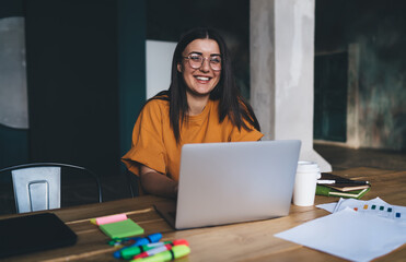 Smiling woman working on laptop while looking at camera