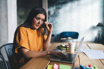 Thoughtful woman sitting at laptop and looking at screen