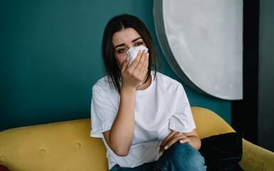 Ill woman wiping running nose at home