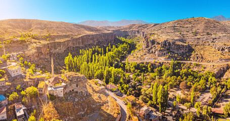 Aerial view of a Famous and popular tourist attraction of Cappadocia and Turkey - Ihlara Valley with a deep gorge and steep cliffs with village and mosque minaret