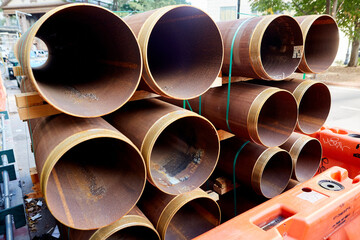 Rusted Pipes with Threaded Ends in Stacks with Green Straps on Construction Site, Horizontal View...