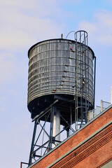 Grey Water Tower with Ladder on Red Brick Building in NYC