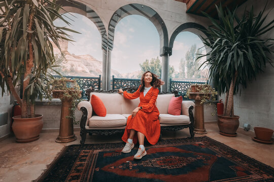 A girl sits comfortably in an authentic Turkish hotel in Cappadocia, surrounded by the region's unique and exotic architecture.