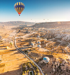 Beautiful aerial panoramic view of the valley in Cappadocia with magical flying balloons and at sunrise. Travel and vacation in Turkey.