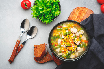 Hot vegetable soup with chicken, corn and green beans. Comfort food. Gray table background, top view