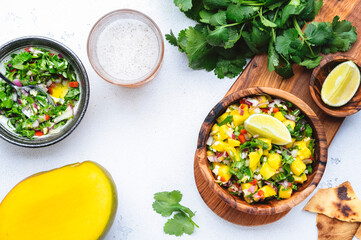 Spicy mango salsa sauce with red chili peppers, onion, garlic, lime and cilantro, white table background, top view