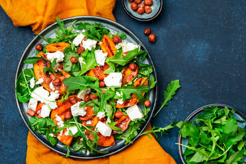 Delicious grilled peach salad  with cheese, hazelnuts and arugula on blue background, top view