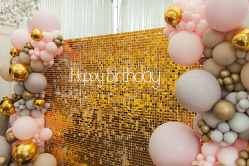 A large festive photo zone for a birthday, decorated with gold sequins, pink, gray and gold balloons of different sizes. Celebrating concept