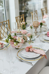 Wedding decorations. Served wedding table with decorative fresh pink flowers and candles. Celebration details. Flower composition roses plates and candles in candlesticks