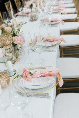 Wedding decorations. Served wedding table with decorative fresh pink flowers and candles. Celebration details. Flower composition roses plates and candles in candlesticks