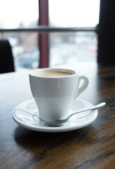 Close up white cup of coffee latte on wood table in cafe