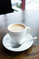 Close up white cup of coffee latte on wood table in cafe