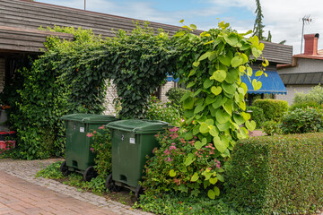 Sweden, Knislinge – July 7, 2022: Two green trash cans on the wheels near a private house