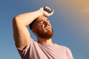 portrait of tired sick exhausted man, handsome guy is suffering from hot Summer heat stroke,...