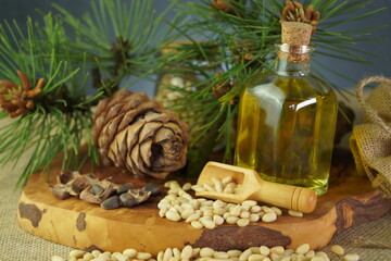 Obraz na płótnie Canvas Cedar and spruce essential oil in glass bottle with pine nuts, cones composition