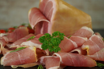Traditional Italian smoked dry ham close-up composition with basil and tomato