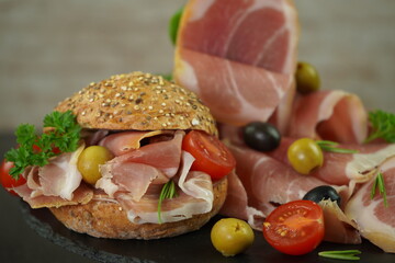 Traditional sliced Spanish dry smoked ham composition with burger and olives