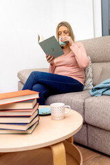 World Book Day concept. Young blonde woman drinking coffee reading a book.