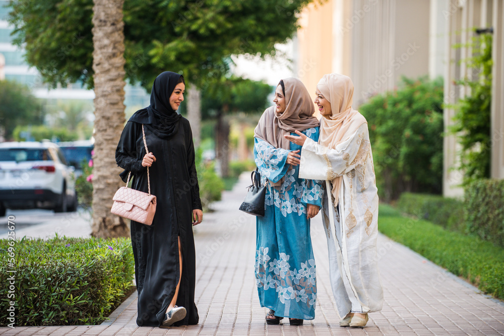 Wall mural three women friends going out in dubai. girls wearing the united arab emirates traditional abaya