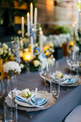 Close-up of a festive table setting. Silver plate decorated with a blue napkin and white natural...